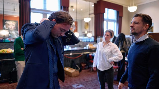 Suppoost Djan Copijn strikt de stropdas onder toeziend oog van Davy Nefs van Suit Up c Eduardus Lee